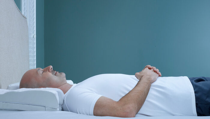 man back-sleeping on a contoured white pillow