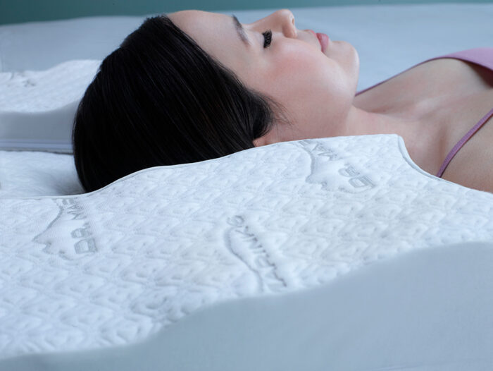 woman shown sleeping on a contoured white pillow