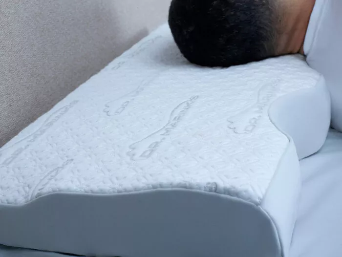 man sleeping on a contoured, white pillow