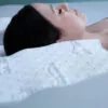 woman shown sleeping on a contoured white pillow